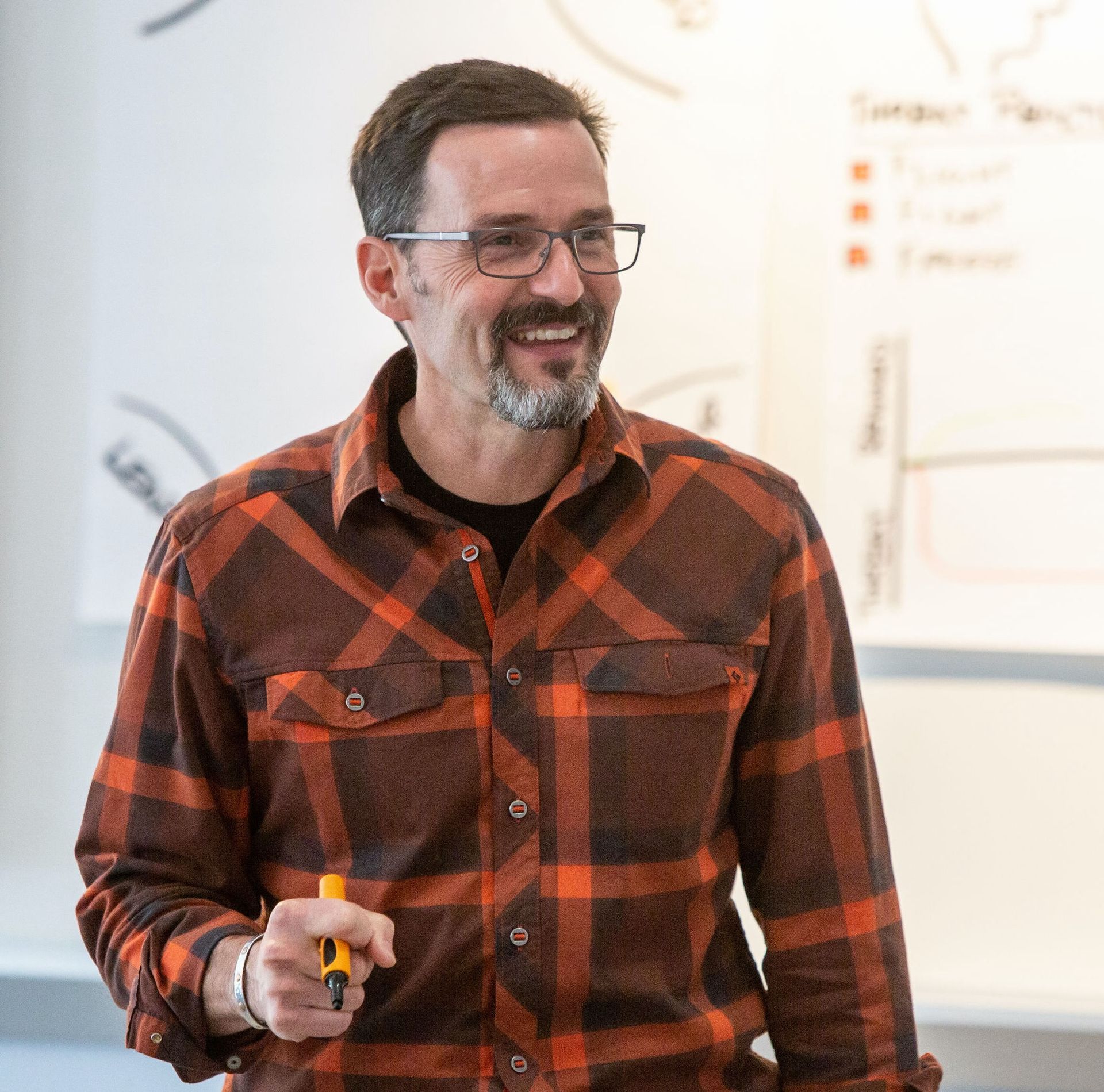 A man wearing glasses and a plaid shirt is holding a screwdriver