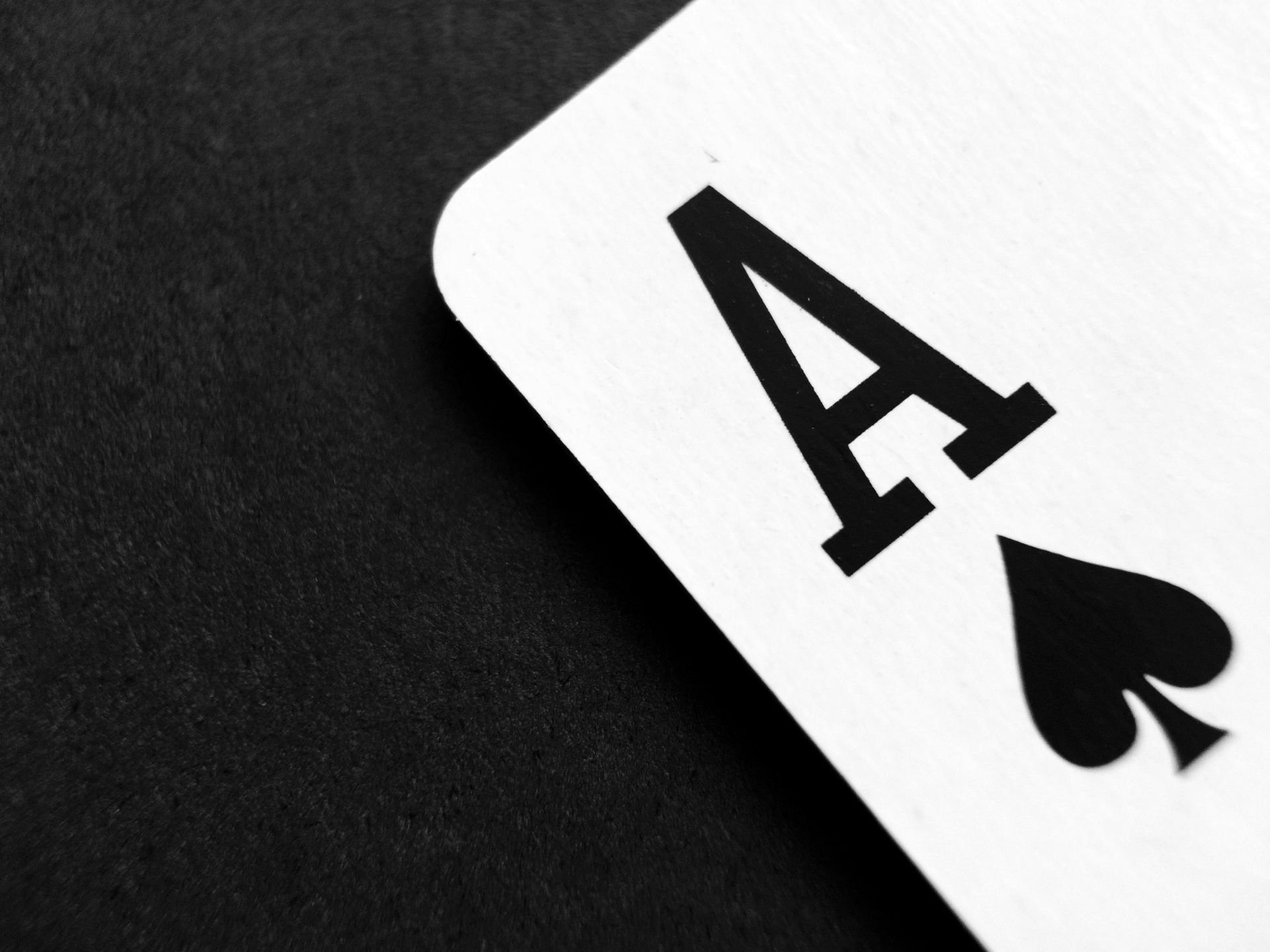 Ace of Spades playing card on a dark surface.
