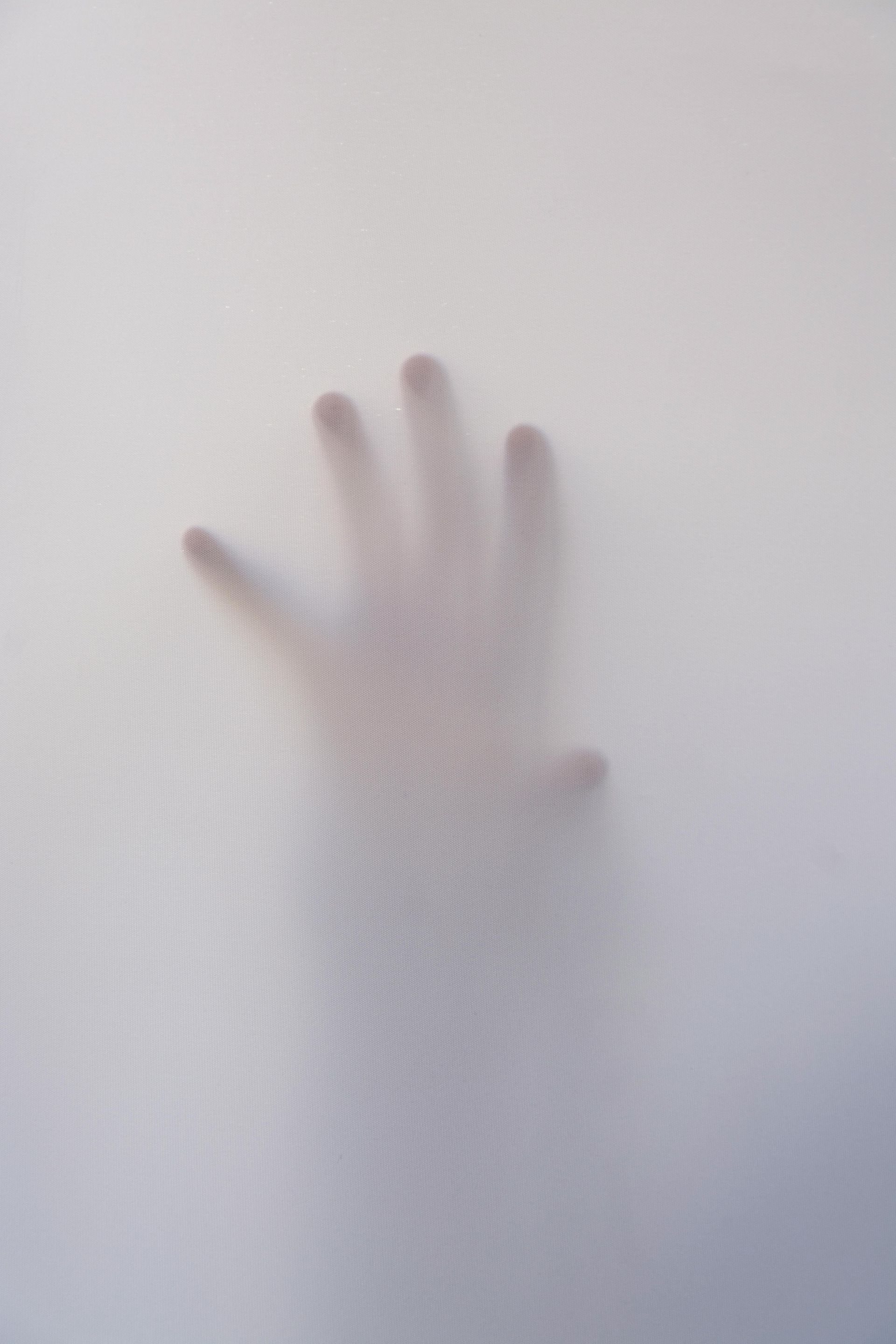 A person 's hand is behind a sheer white cloth.