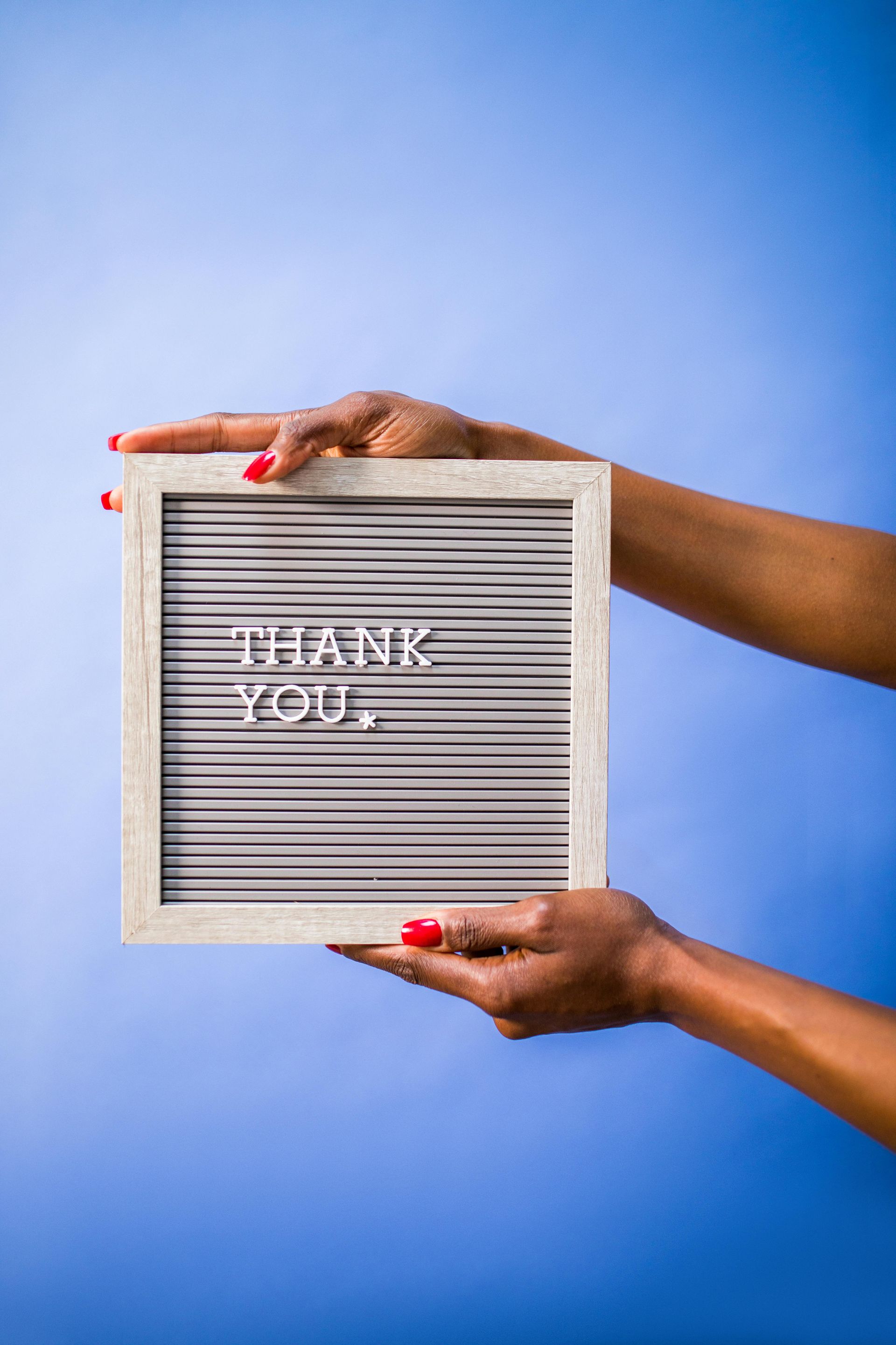 A woman is holding a letter board with the words thank you written on it.