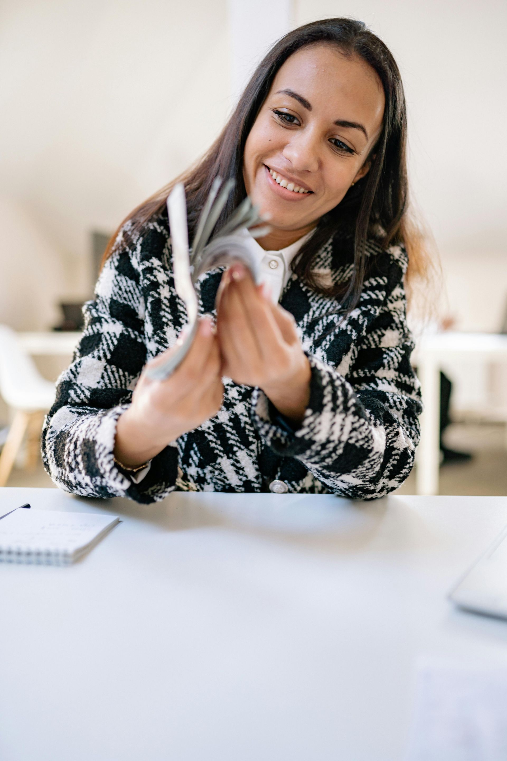 A woman is sitting at a table holding a bunch of money in her hands.