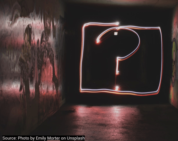 A light drawing of a question mark in a dark room