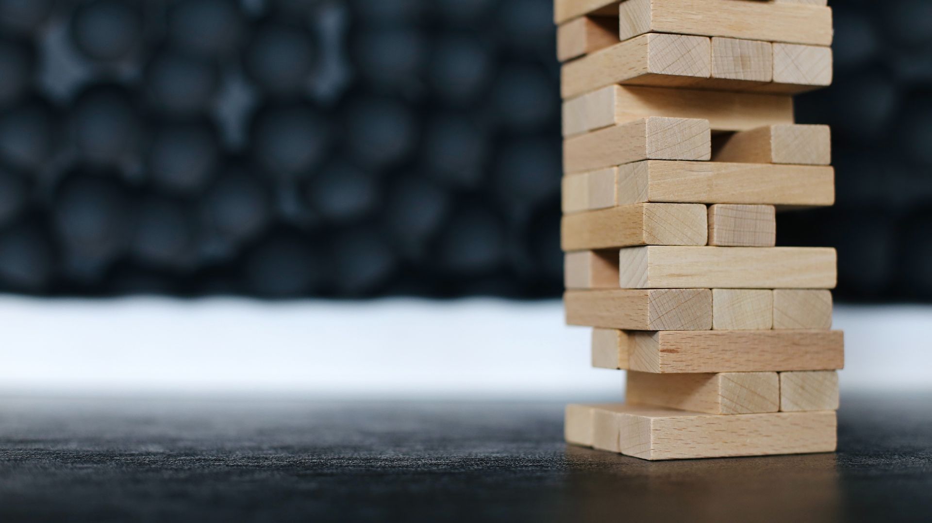 A game of Jenga stacked with a few blocks missing against a dark background