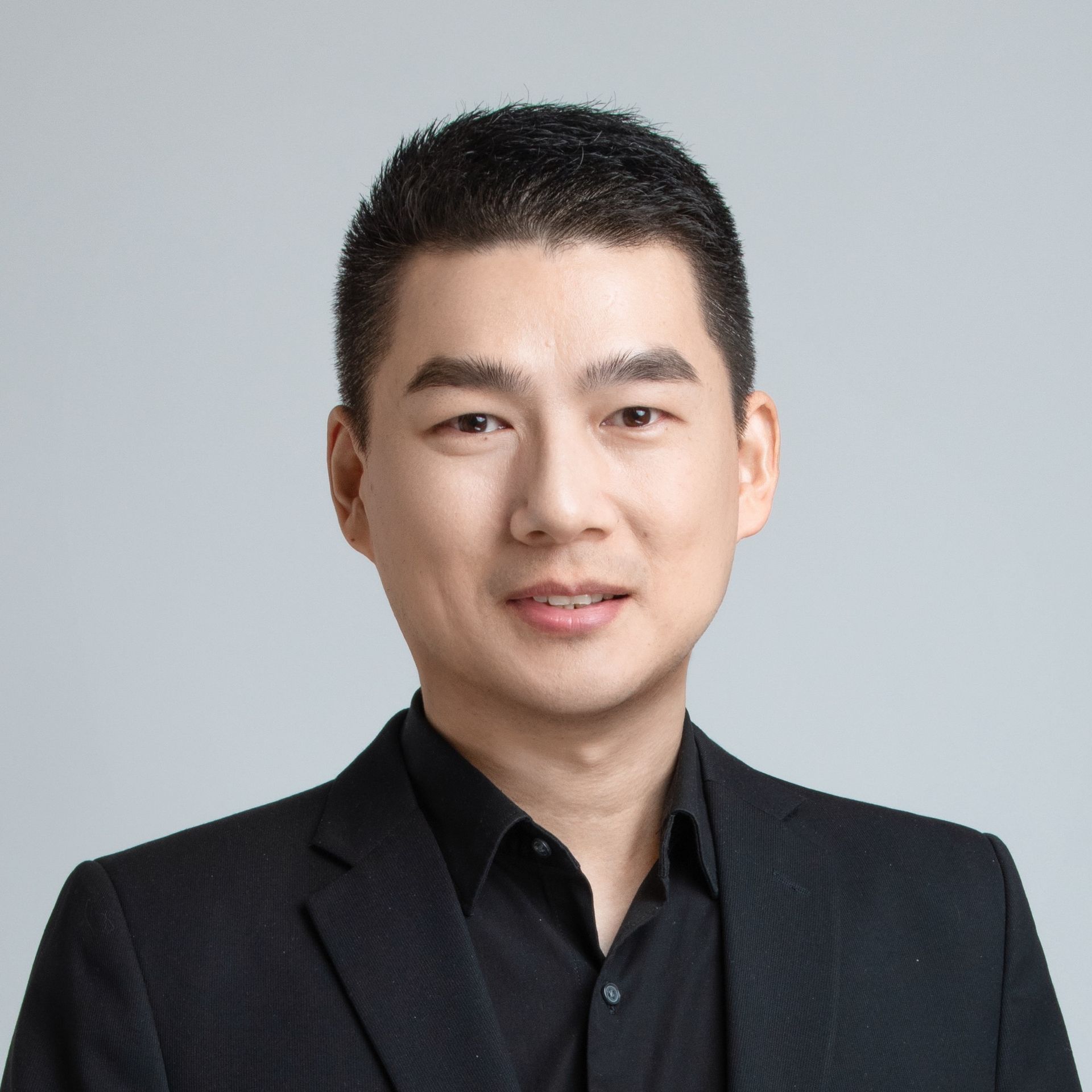 A man in a suit and black shirt is smiling for the camera.