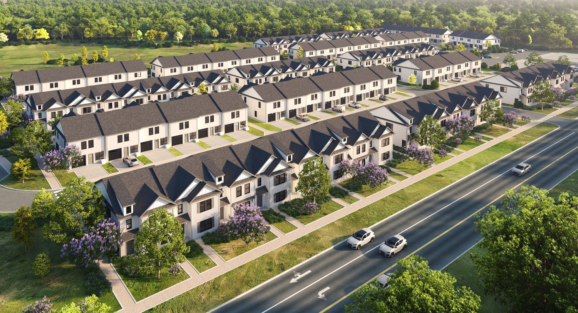 Aerial view of a planned suburban neighborhood with rows of townhouses and a road lined with trees.