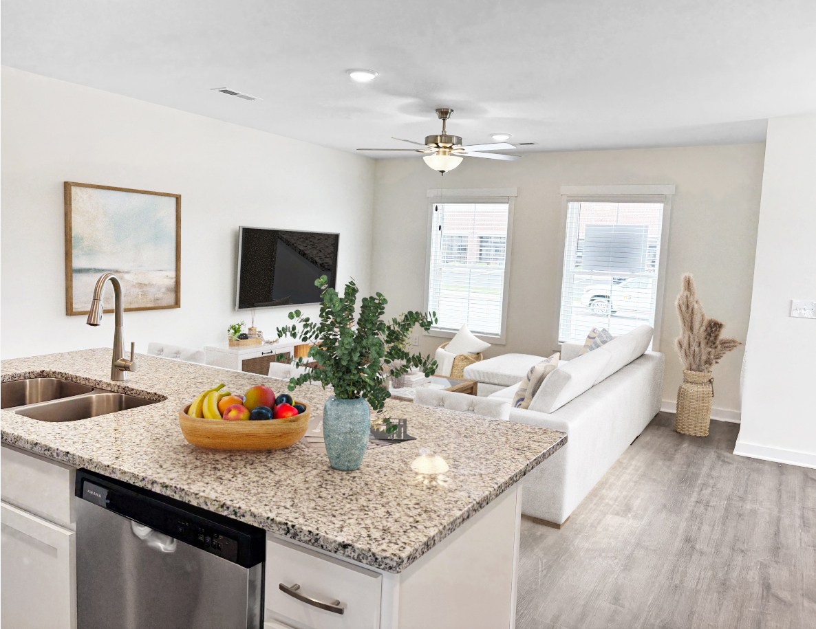 Open-concept kitchen and living room with granite countertop, white sofa, and artwork.