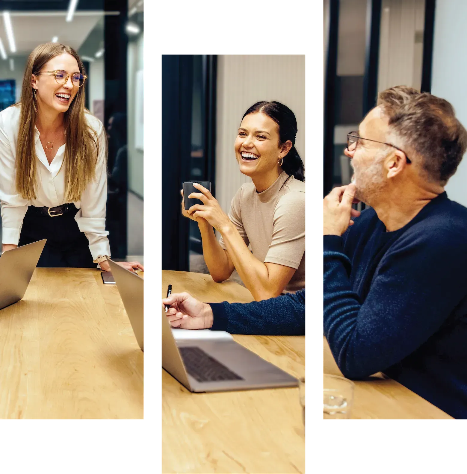 Three coworkers smiling and talking around a conference table in a bright office