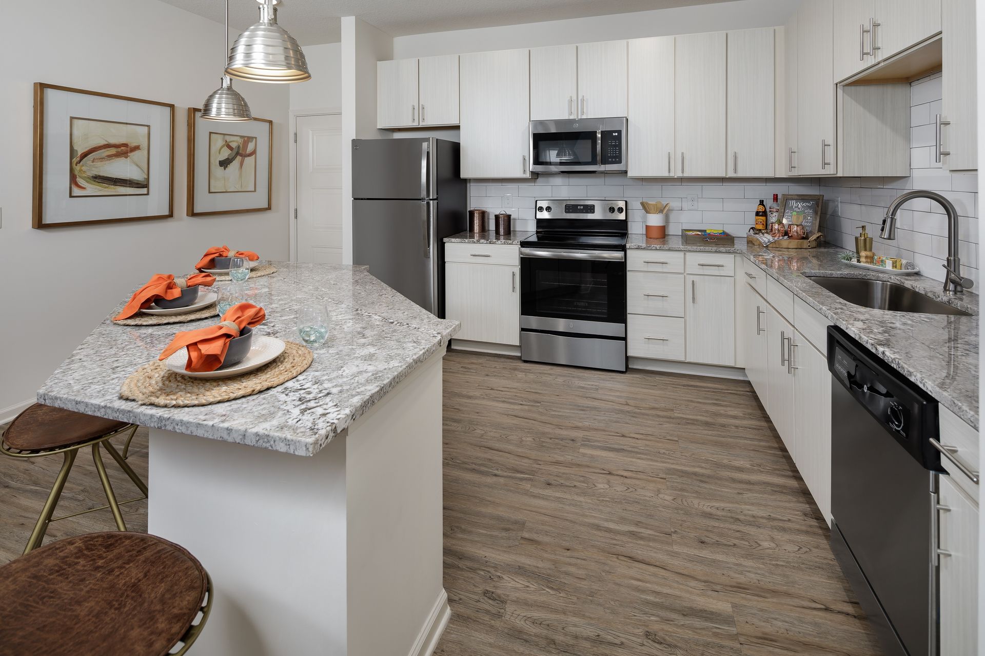 Kitchen with granite countertop, stainless steel appliances, white cabinets, and two bar stools.