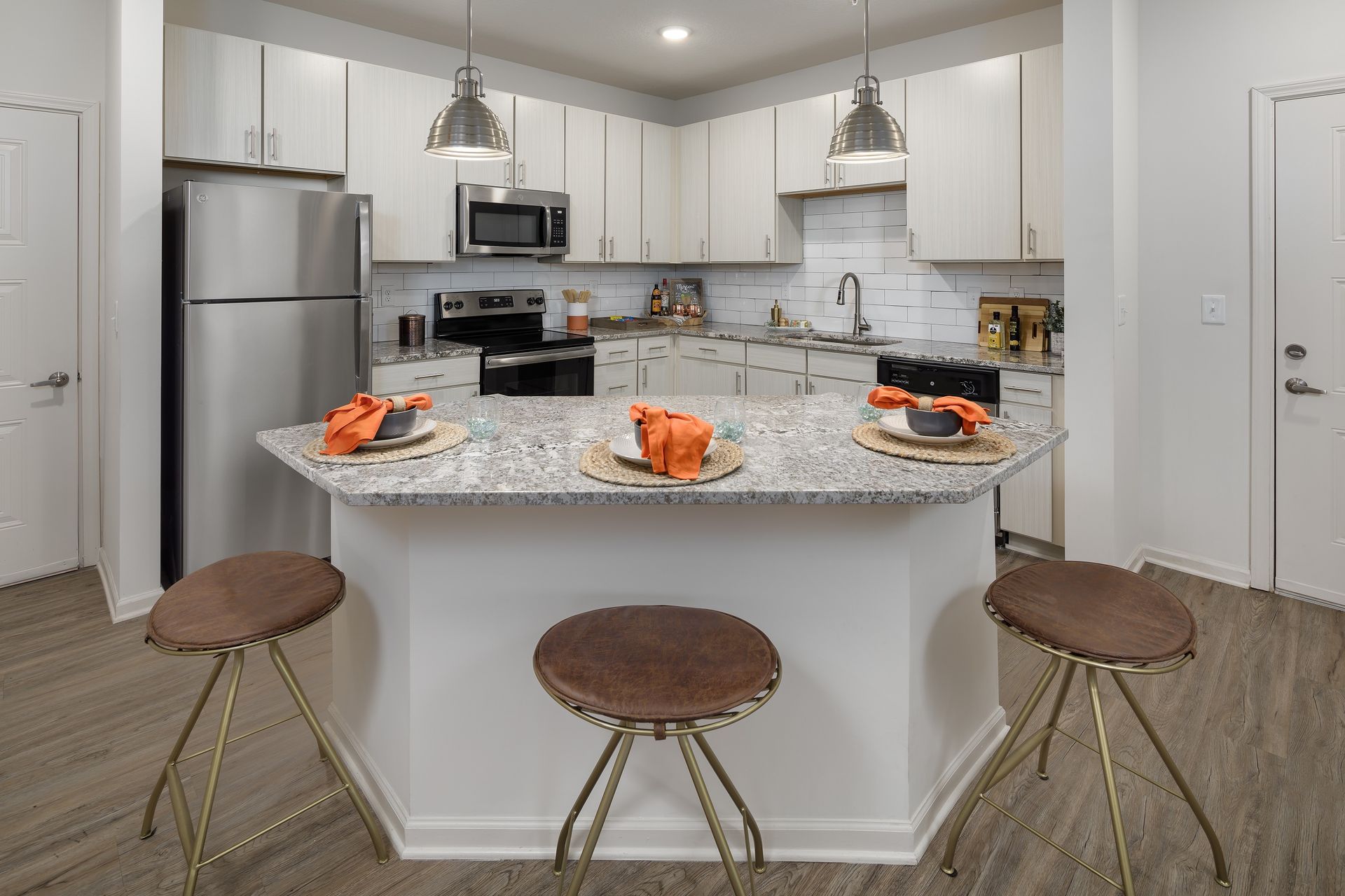 Kitchen with white cabinets, granite countertop island, and brown stools.
