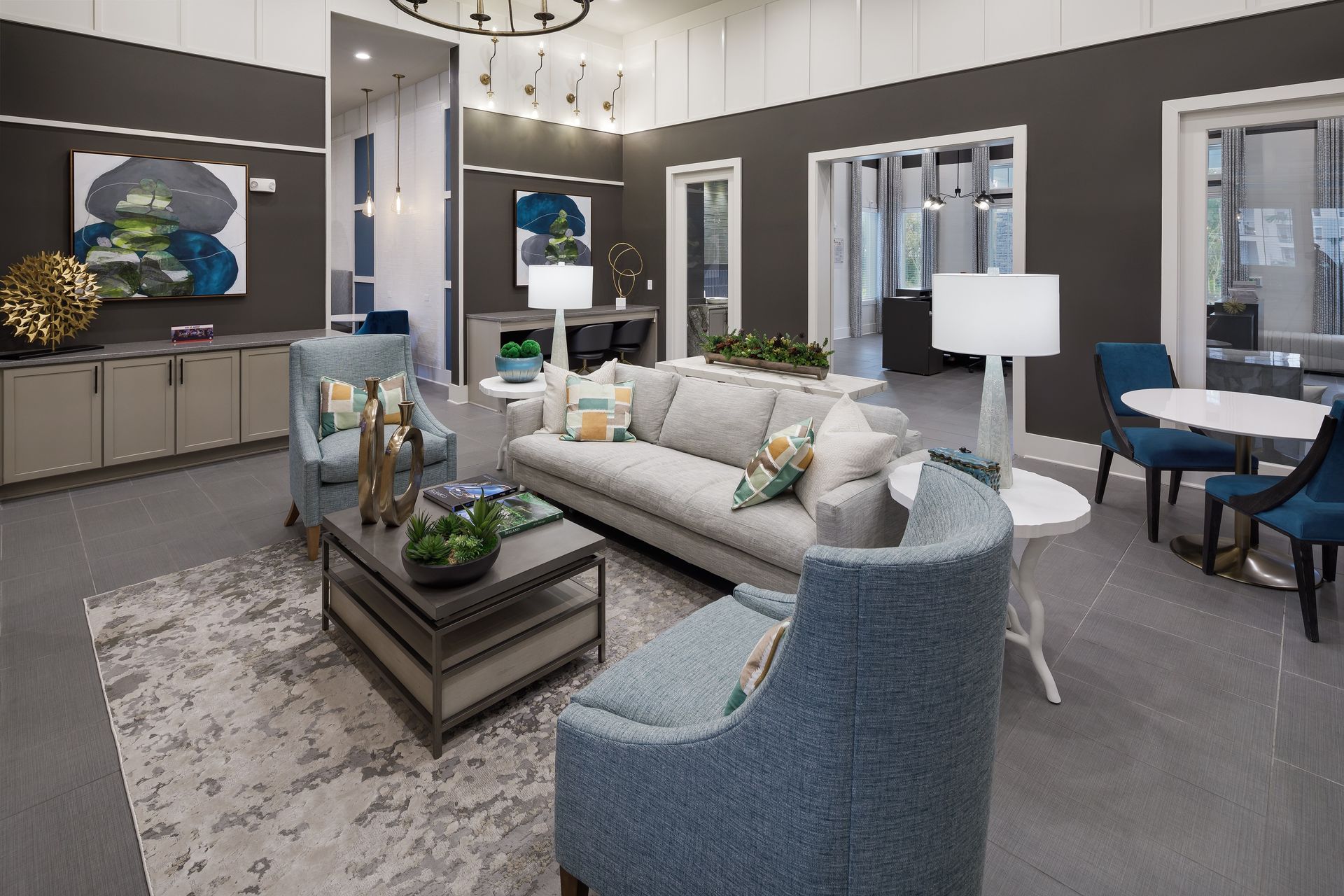 A modern living area with blue and gray accents. A sofa and chairs surround a coffee table.