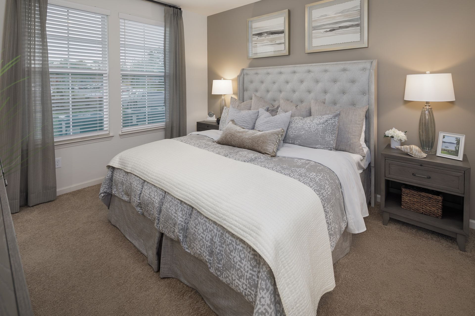 Gray bedroom with a tufted headboard, two lamps, and a double window.