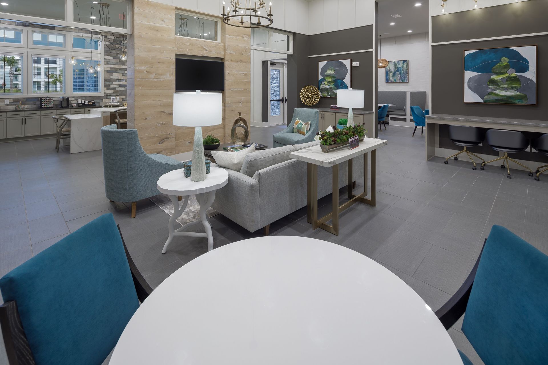 Modern lounge area: light blue seating, neutral sofa, white side tables, decorative art, and open space.