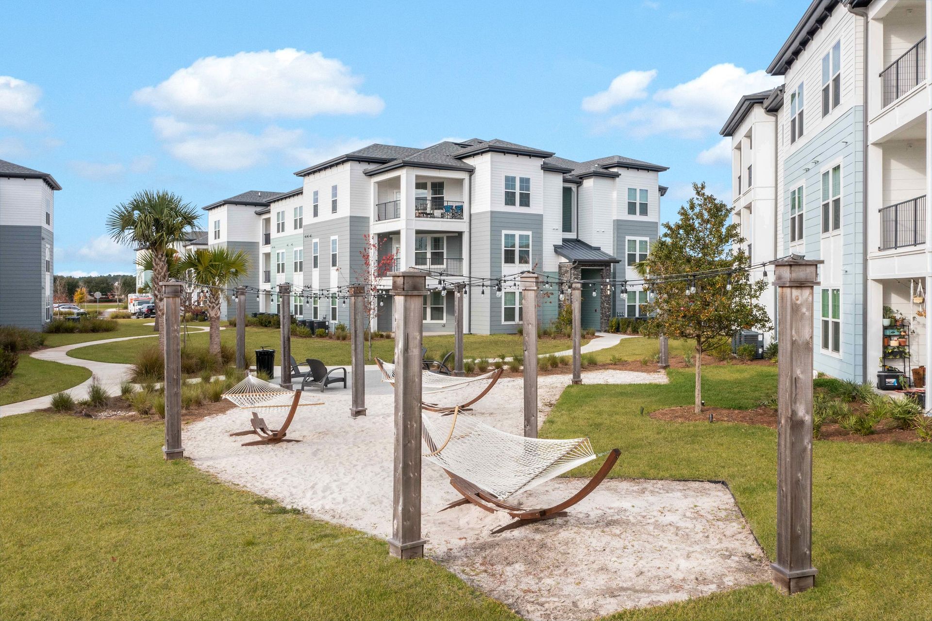 Apartment complex with hammocks in grassy area on a sunny day.