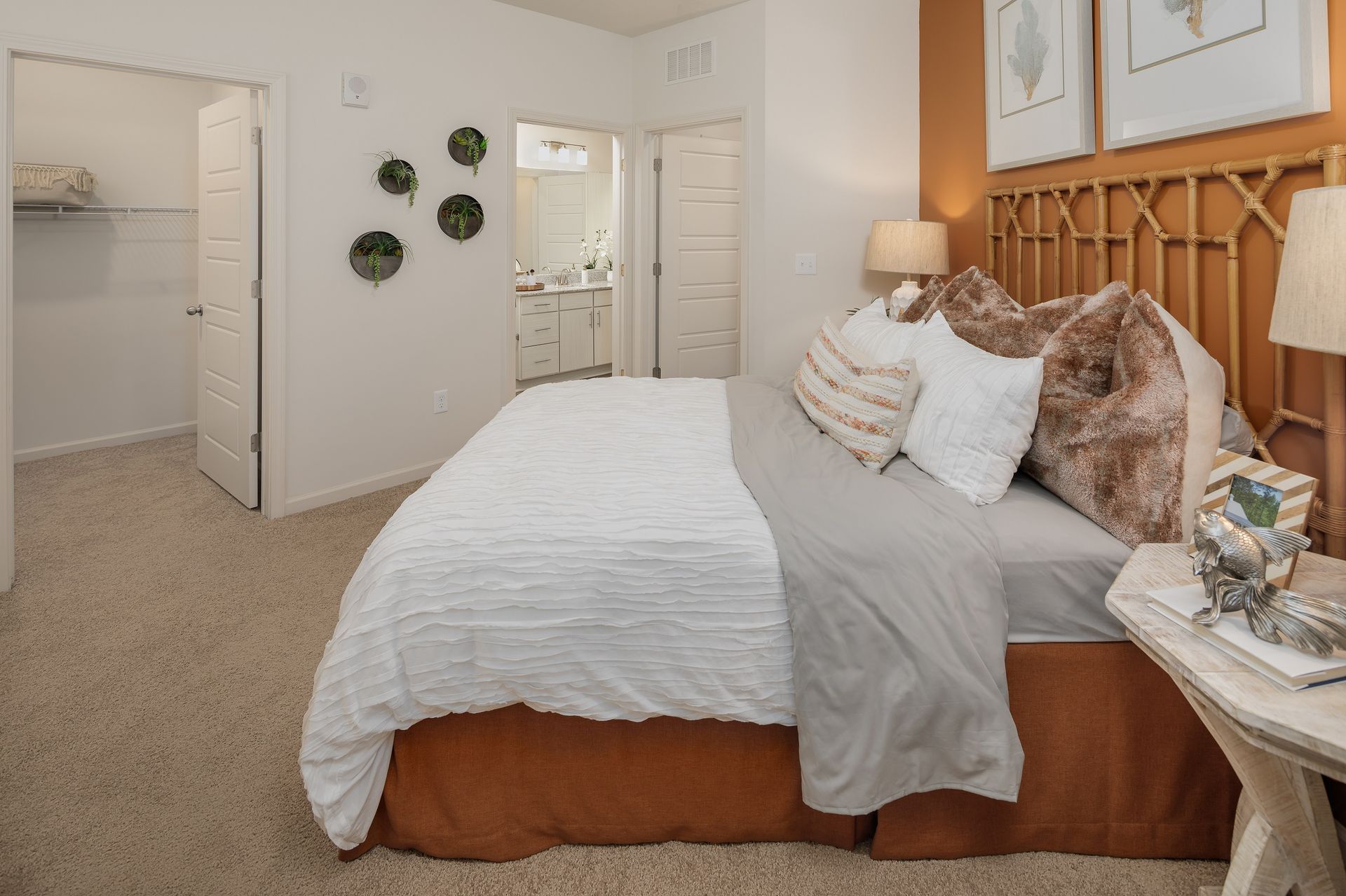 Bedroom with bed, nightstand, and bathroom view; neutral colors, decorative accents.