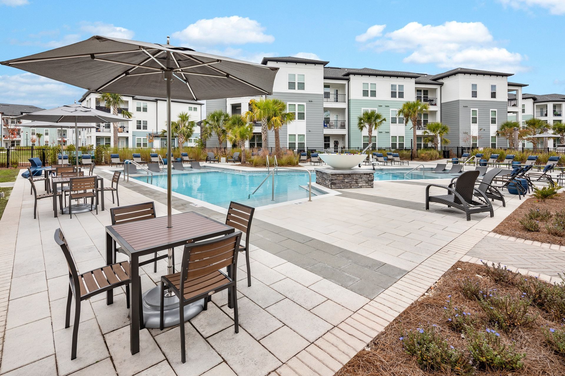 Poolside outdoor seating area at apartment complex with pool and building in background.