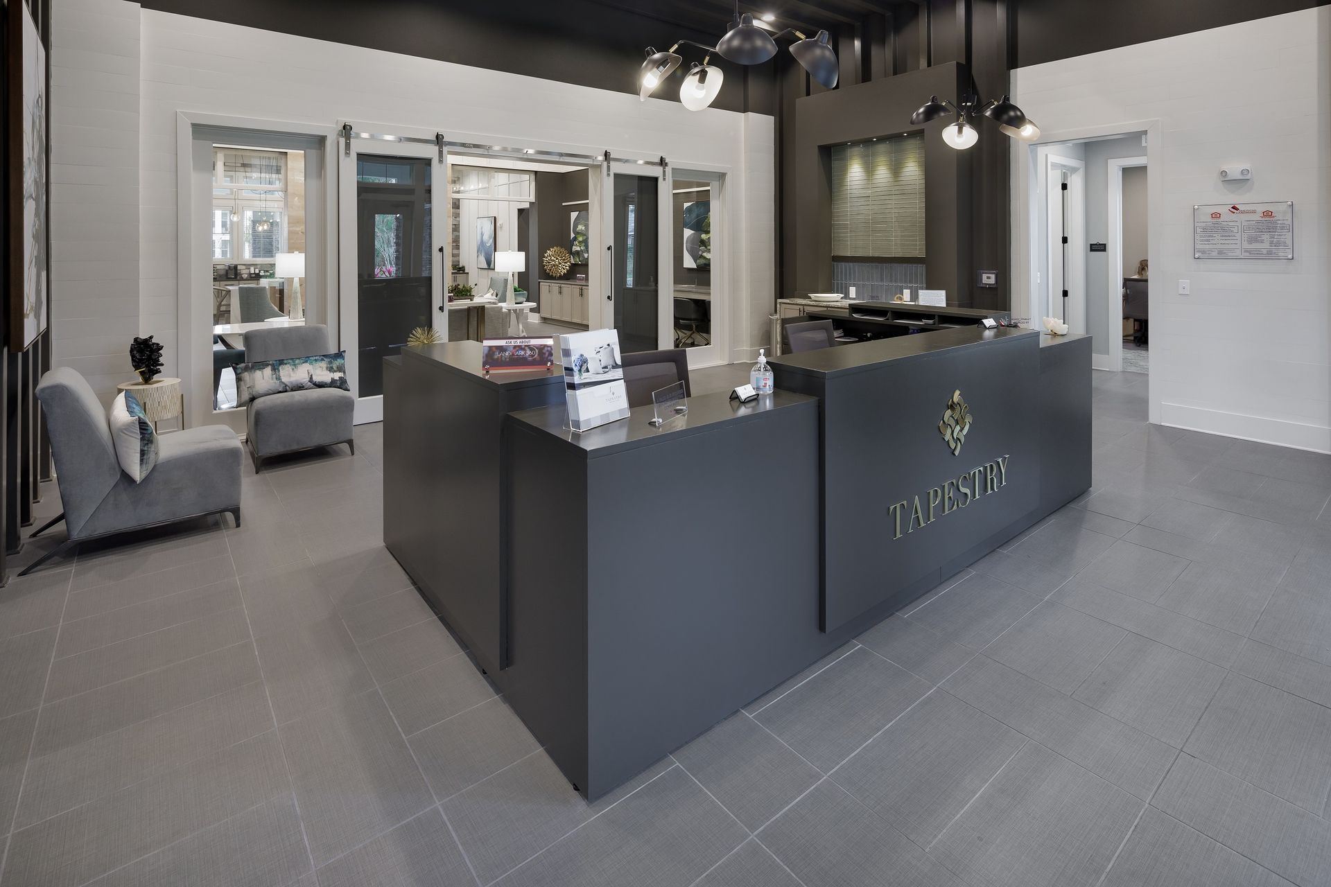 Modern office reception area with gray walls, a dark gray desk, and door displays.