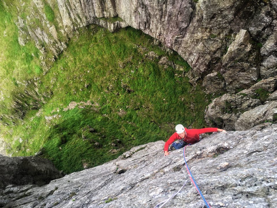 Climber high above a grassy platform