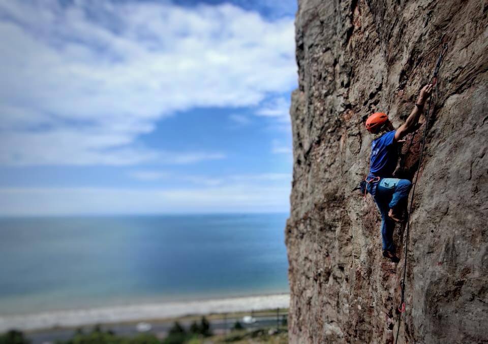 Climber ascending a cliff by the sea