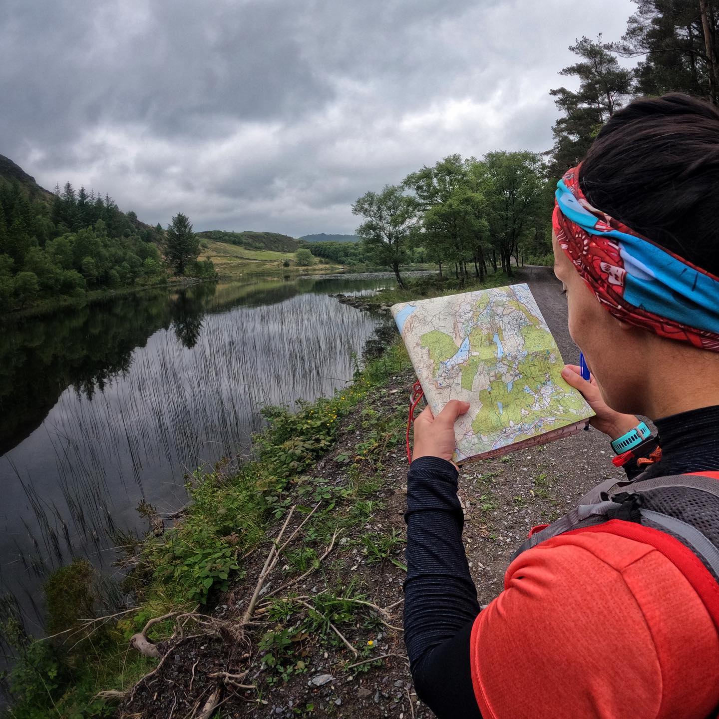 Runner holding a map with a lake view