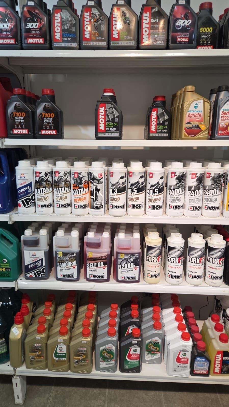 Estanterías de una tienda minorista repletas de botellas de aceite para motores de automóviles de diversas marcas y tamaños.