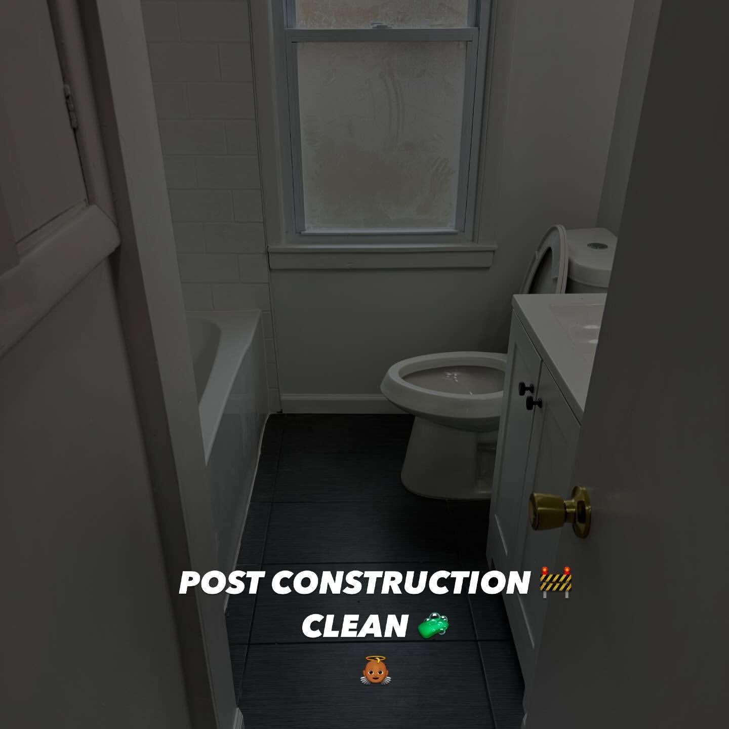 Small bathroom after construction; white walls, black floor, toilet, sink cabinet, and window.