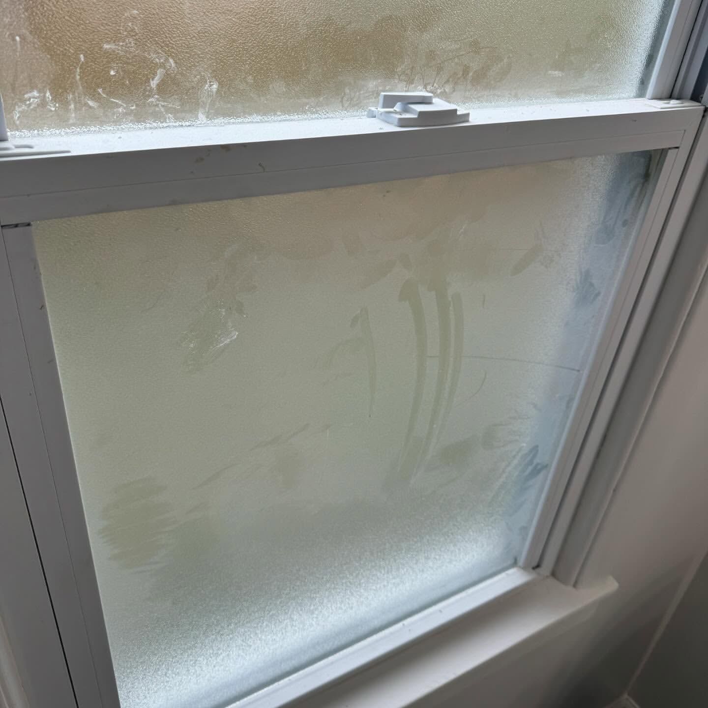 Foggy, frosted window, white frame; condensation obscures the view.