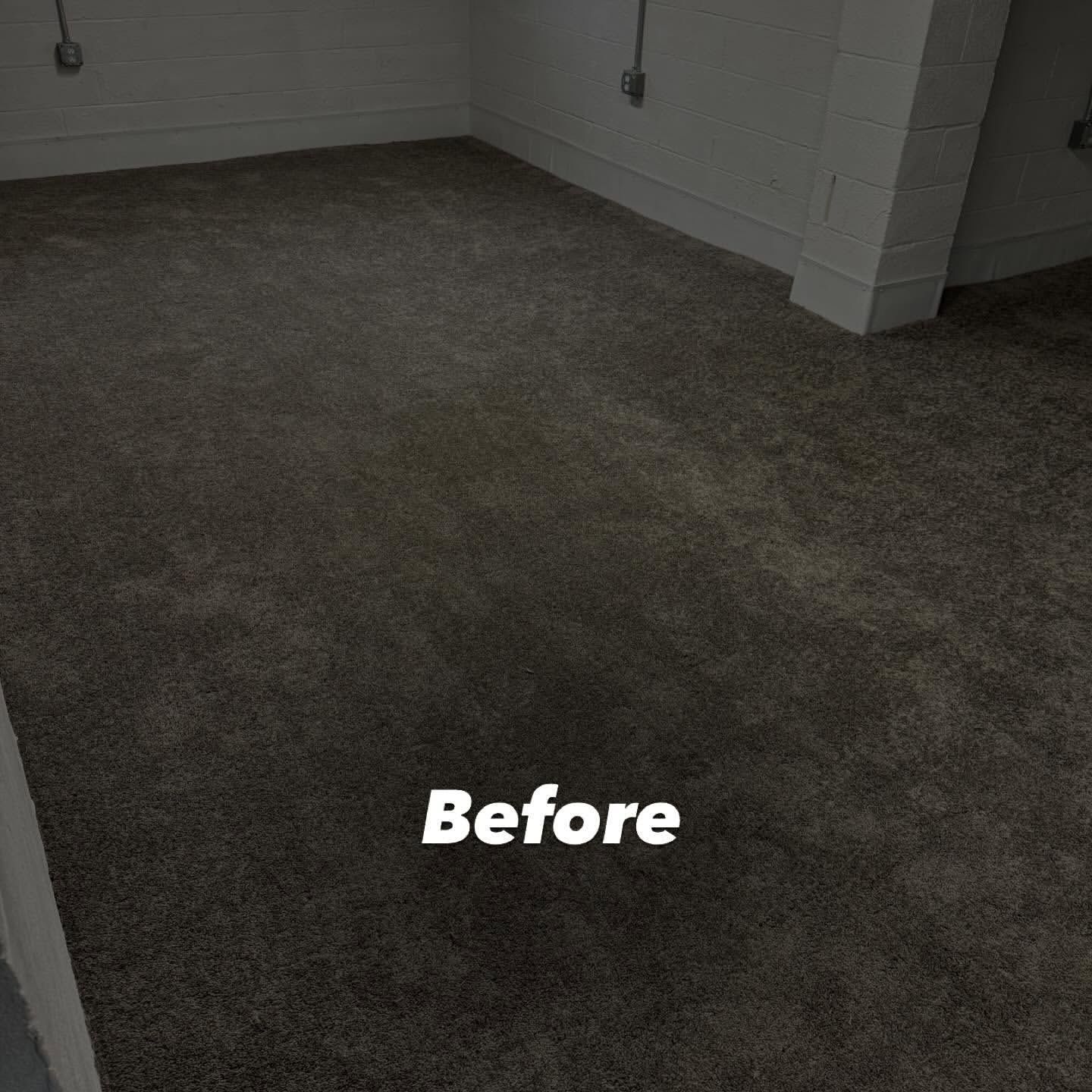 A room with dark gray carpet, white brick wall. 