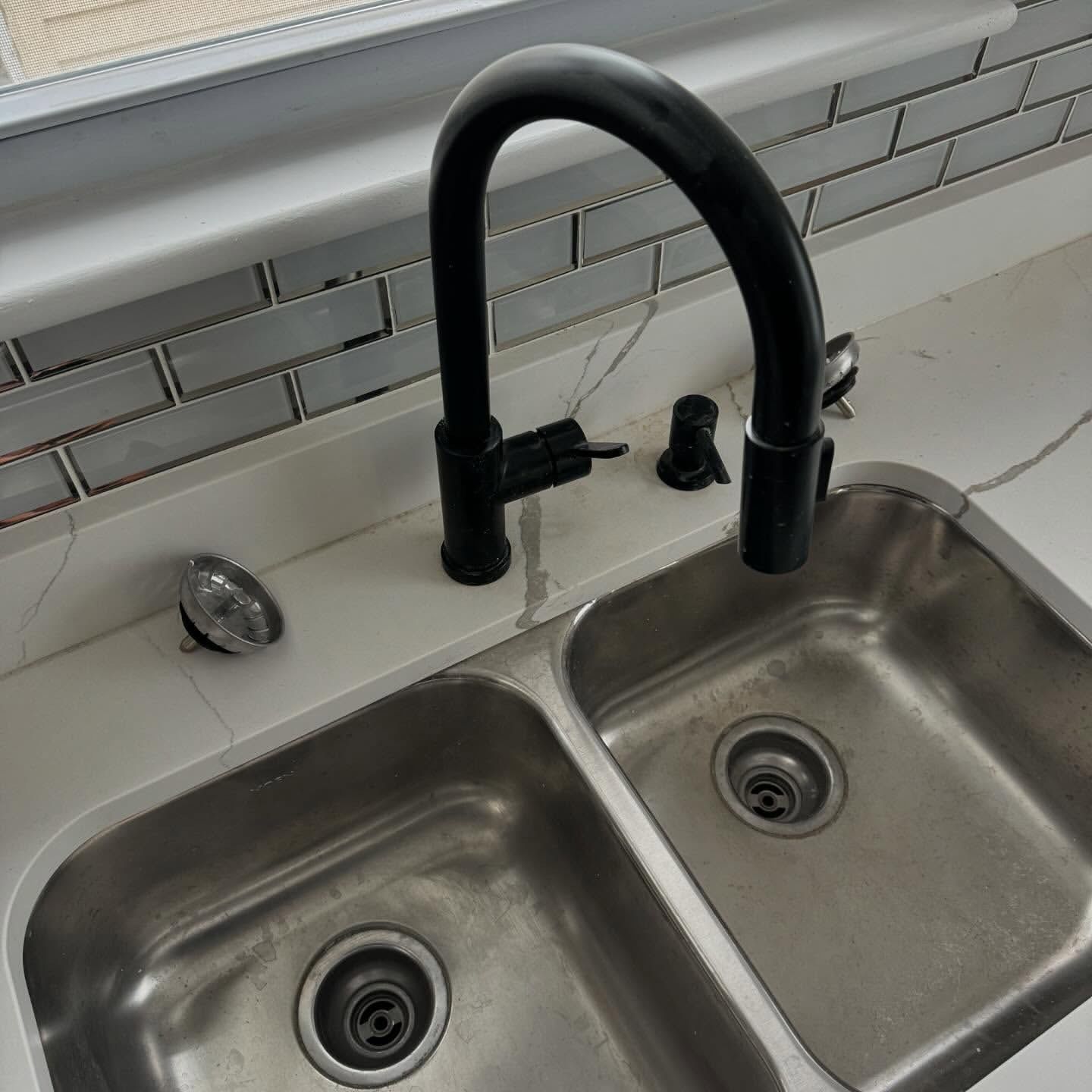 Black faucet over a double stainless steel sink in a kitchen.