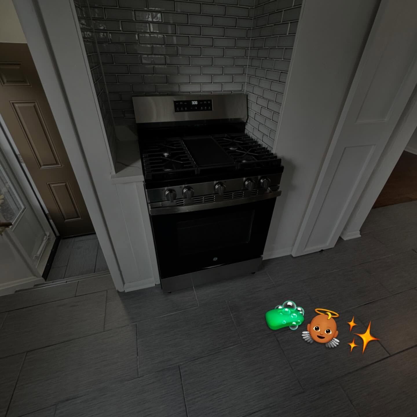 Kitchen with a stove and two emojis: a green object and a smiling face with a halo and sparkles.