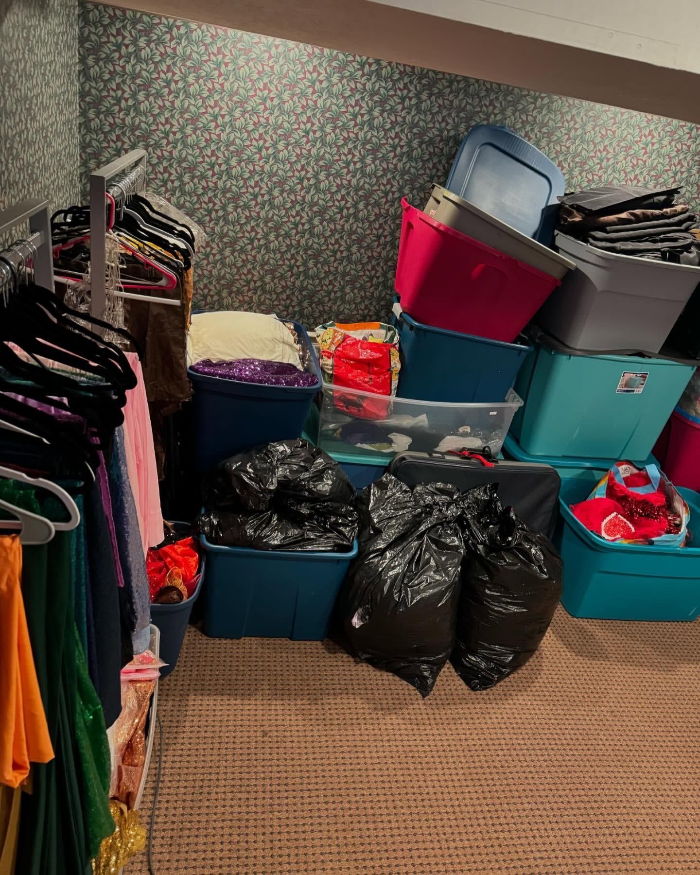 Closet filled with clothes on hangers and storage bins, including garbage bags.