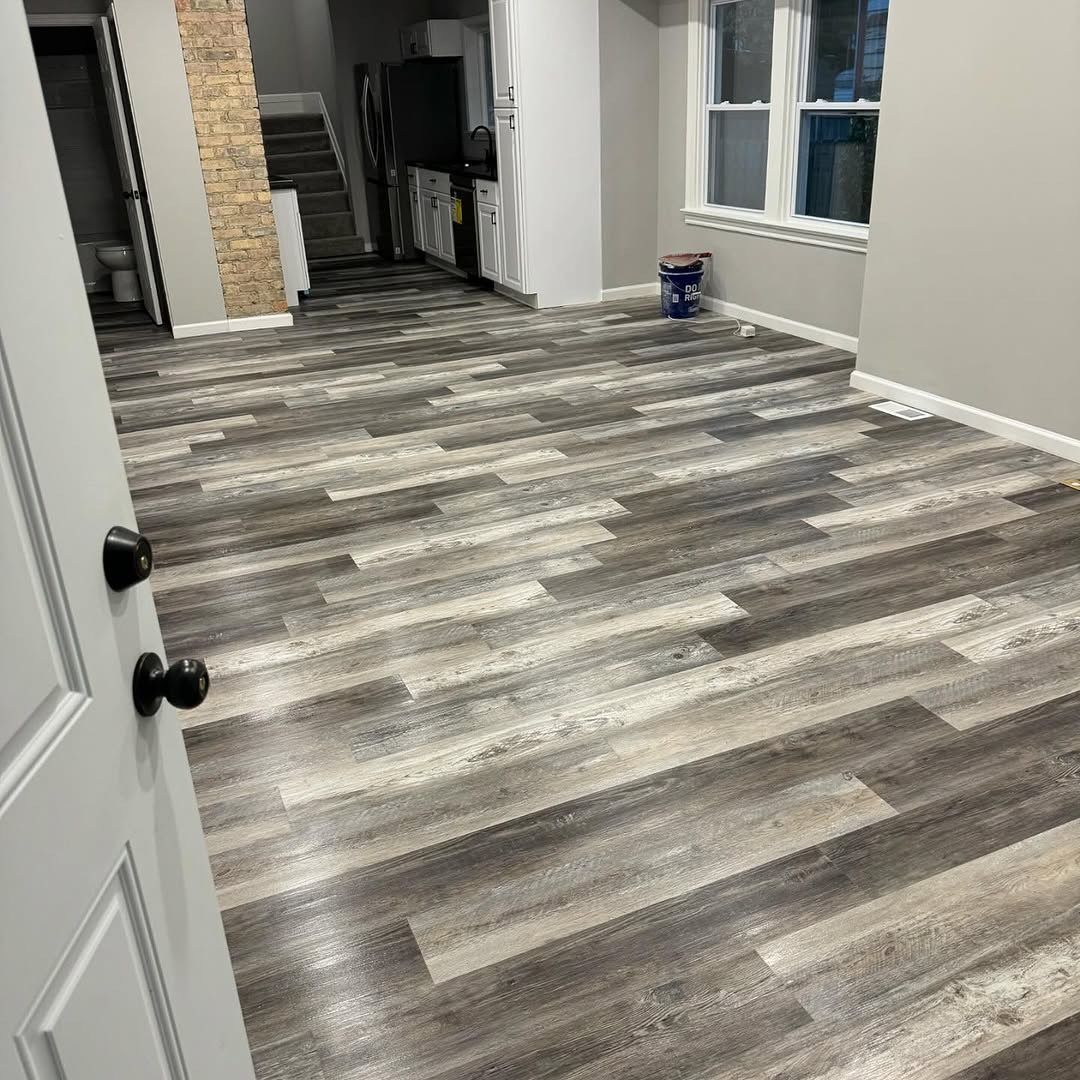 Newly installed gray and white wood-look flooring in a home; view from doorway, looking toward the staircase.