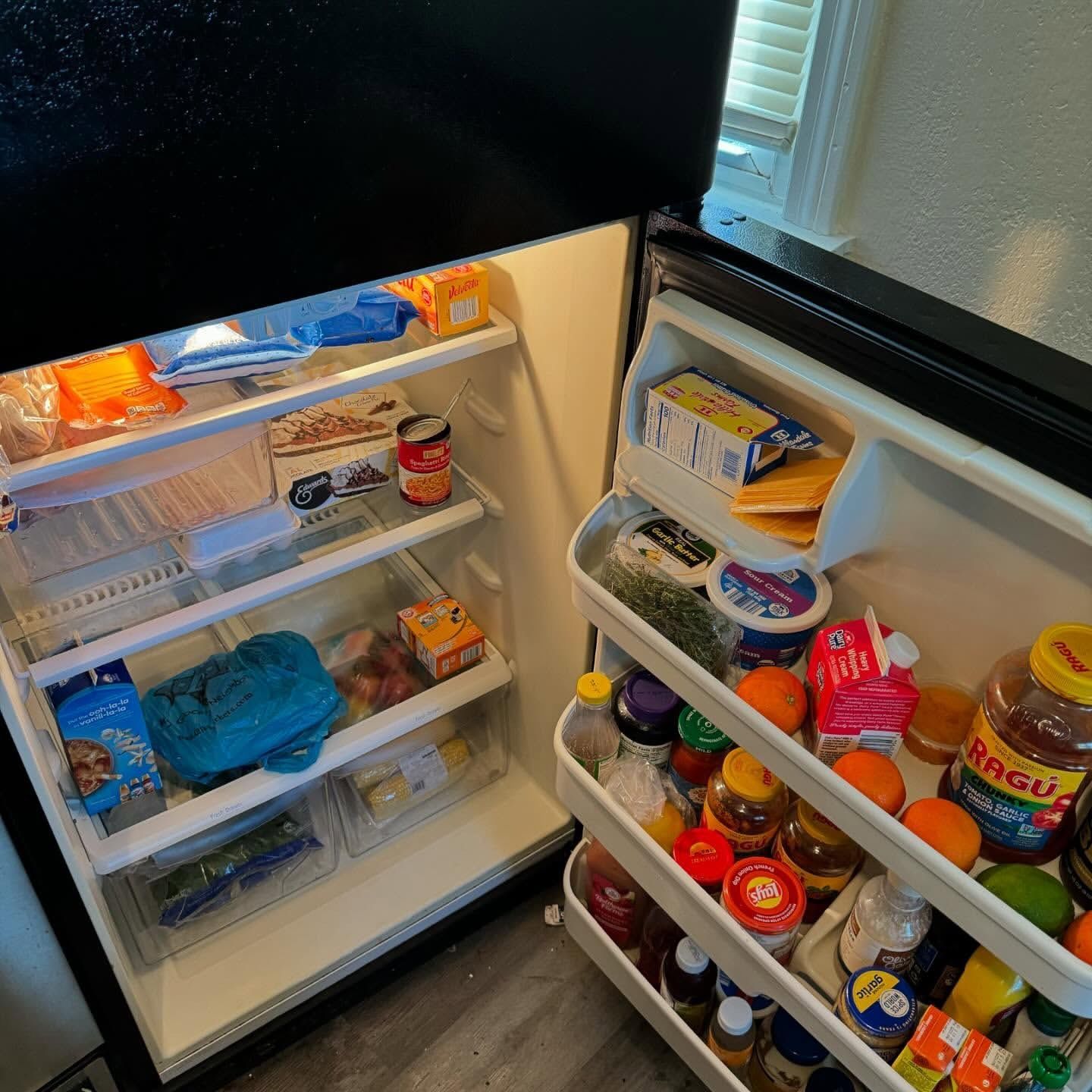 Open refrigerator filled with groceries and condiments.