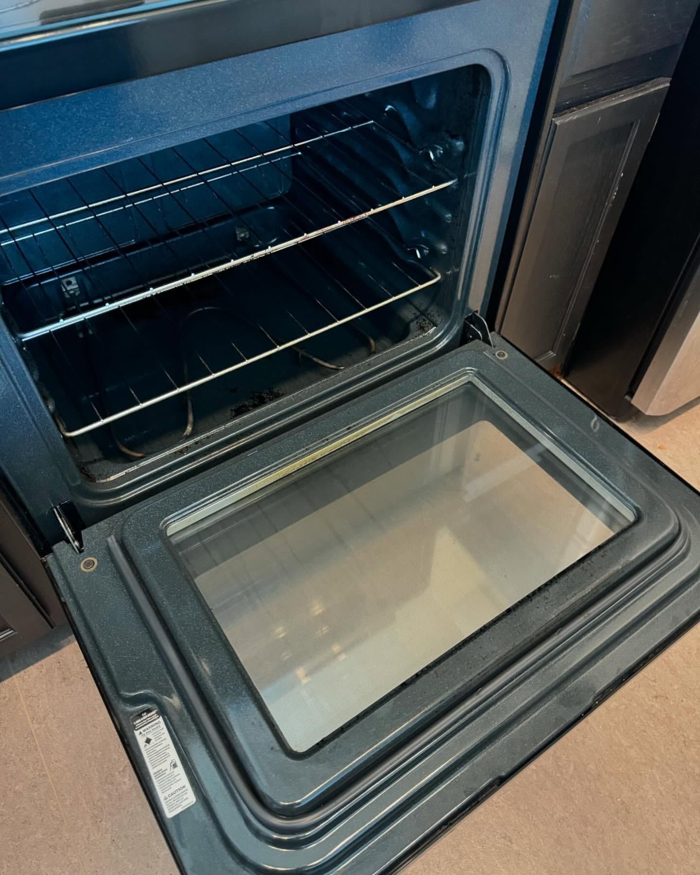 Open black oven with interior racks and glass door.