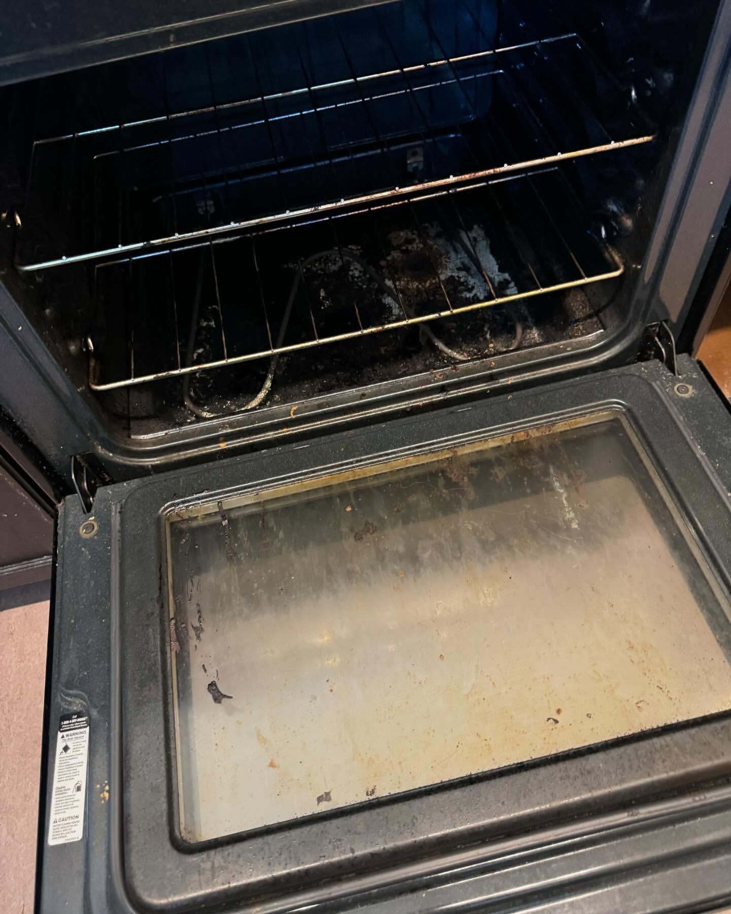 Open, dirty oven with racks and a greasy door.
