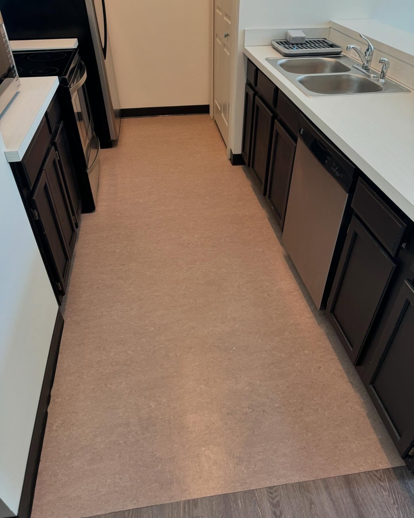 Kitchen with brown cabinets, white countertops, and beige flooring. Stainless steel appliances.