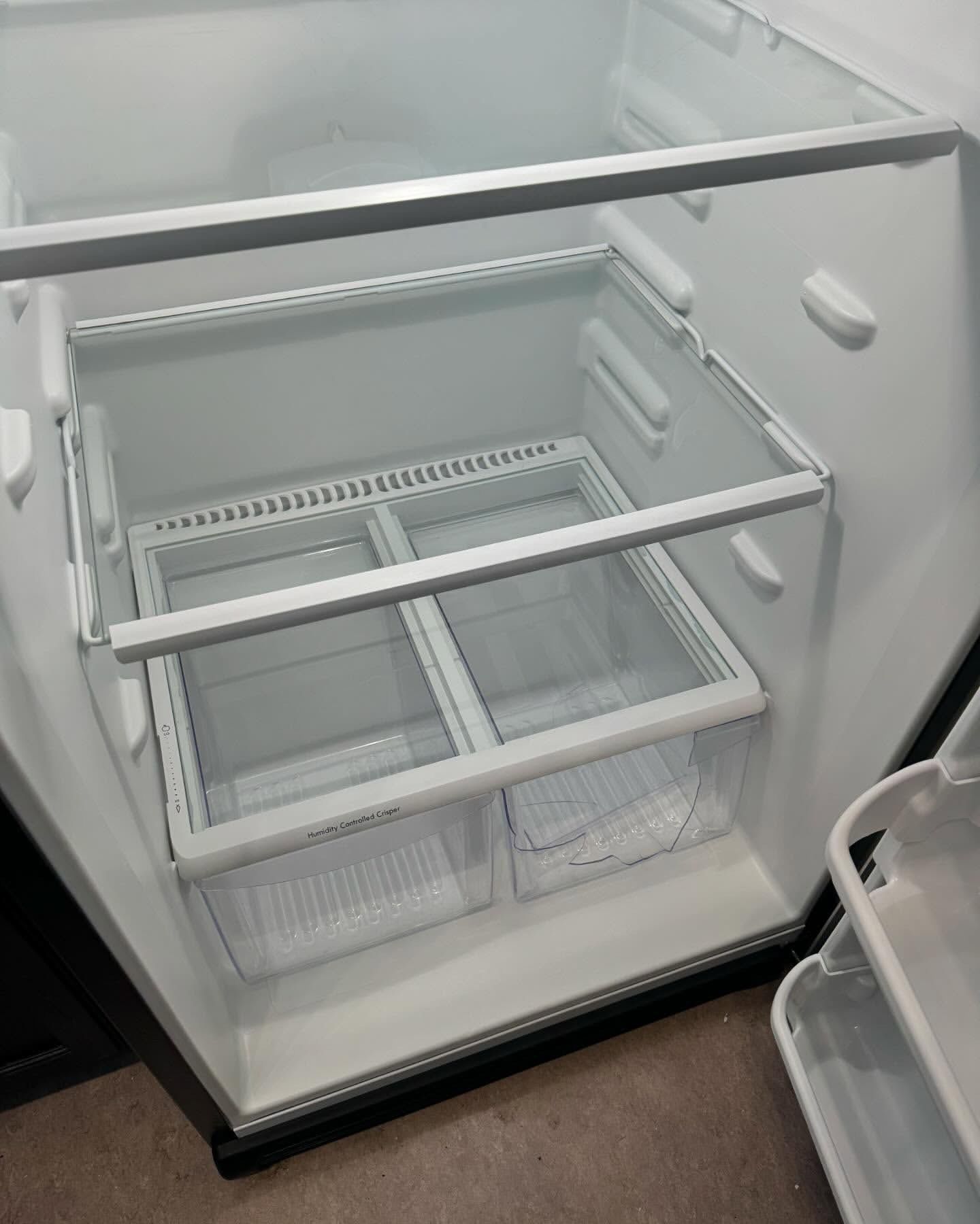 Empty refrigerator interior with glass shelves and two crisper drawers.