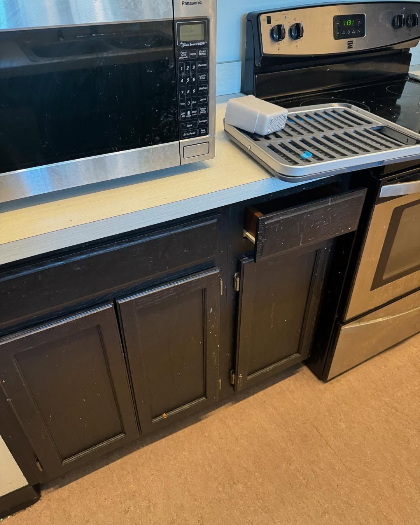 Kitchen counter with microwave, oven, cabinets, and a tray.