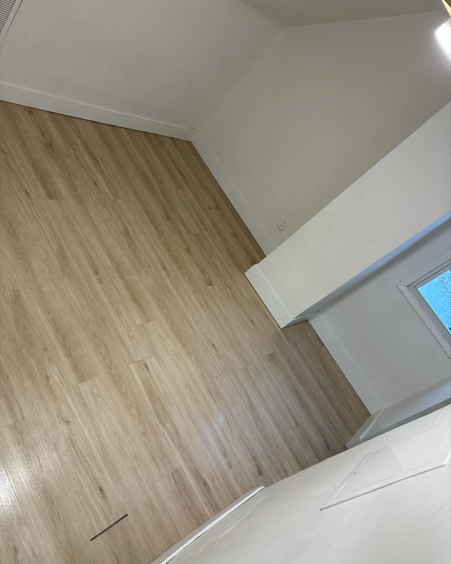 Light wood-look flooring in an empty room with white walls and trim.