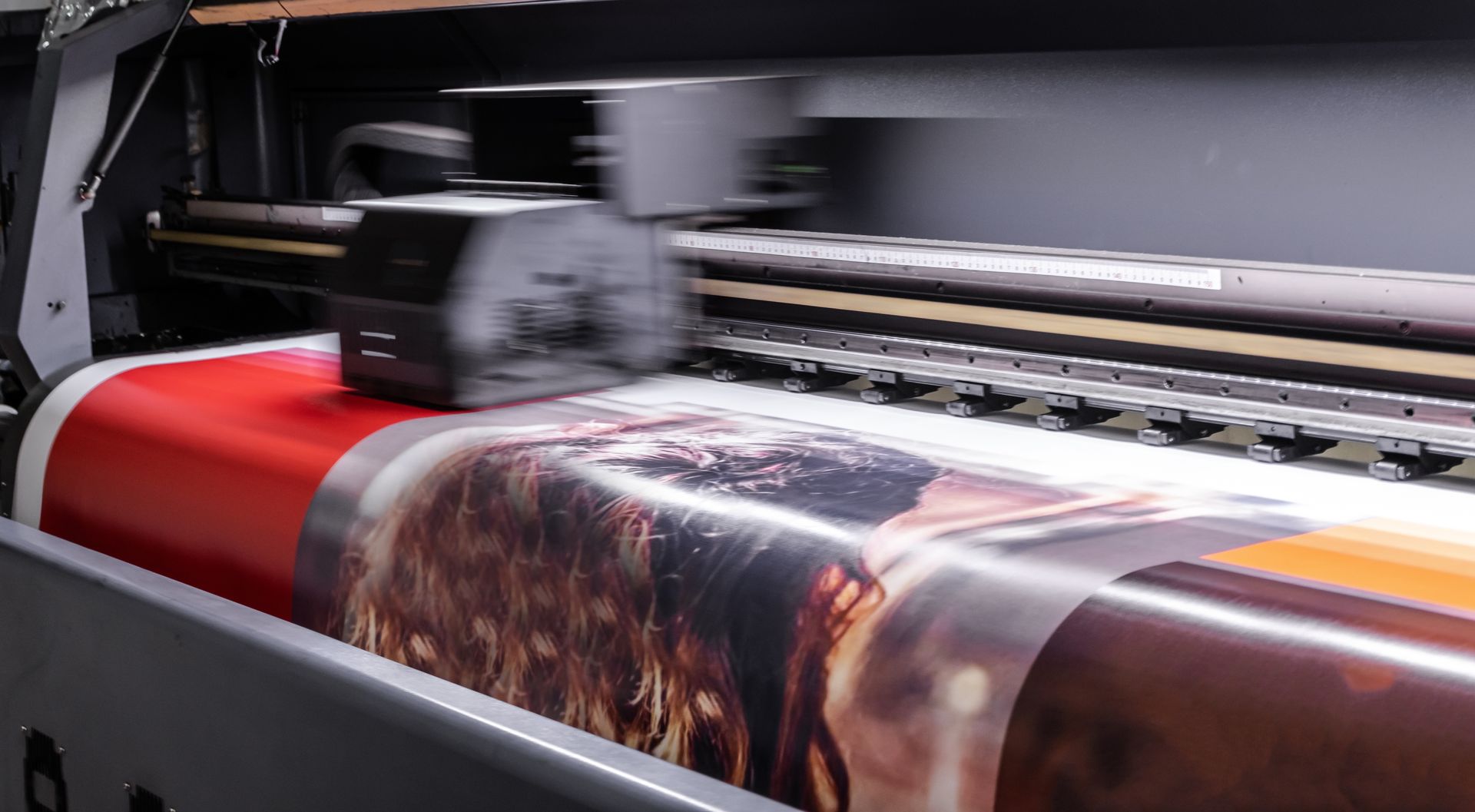Professional plotter executing precise custom digital printing on a heavy-duty vinyl media roll.
