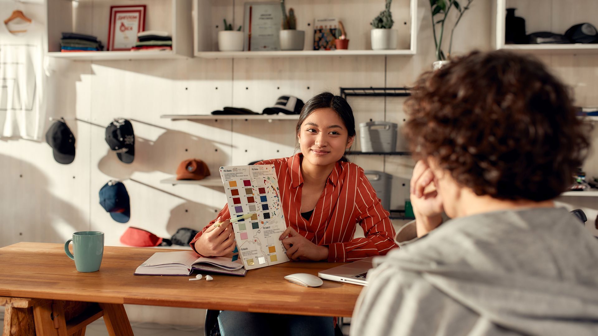 Designer showing a color sample chart to a client in a studio workspace.