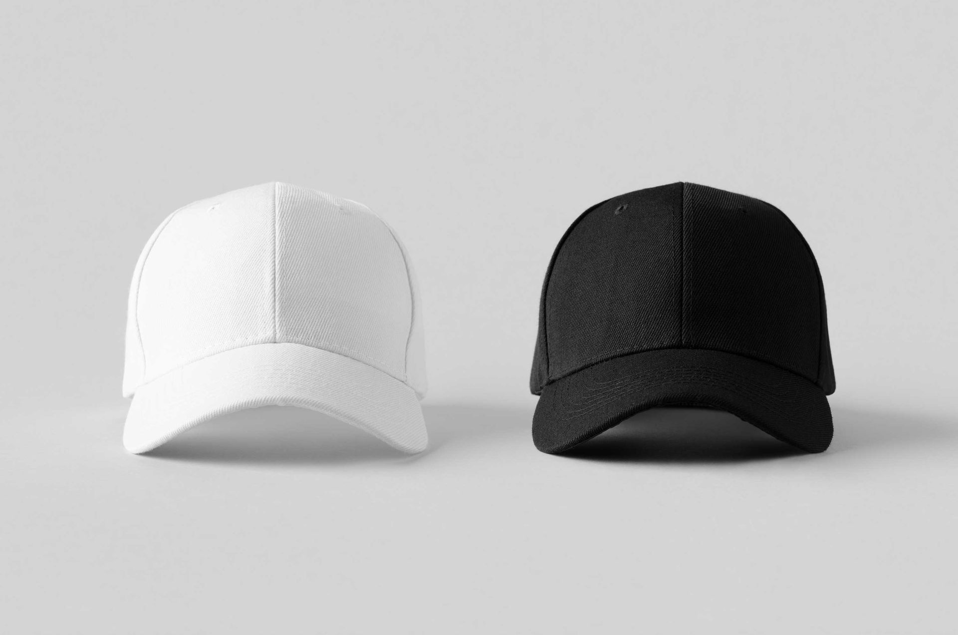 Two branded caps in white and black displayed side by side on a neutral background. Two branded caps in white and black displayed side by side on a neutral background.