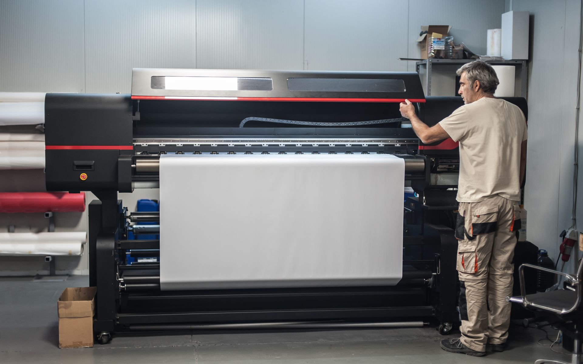 A technician operator works on a large premium industrial printer plotter machine