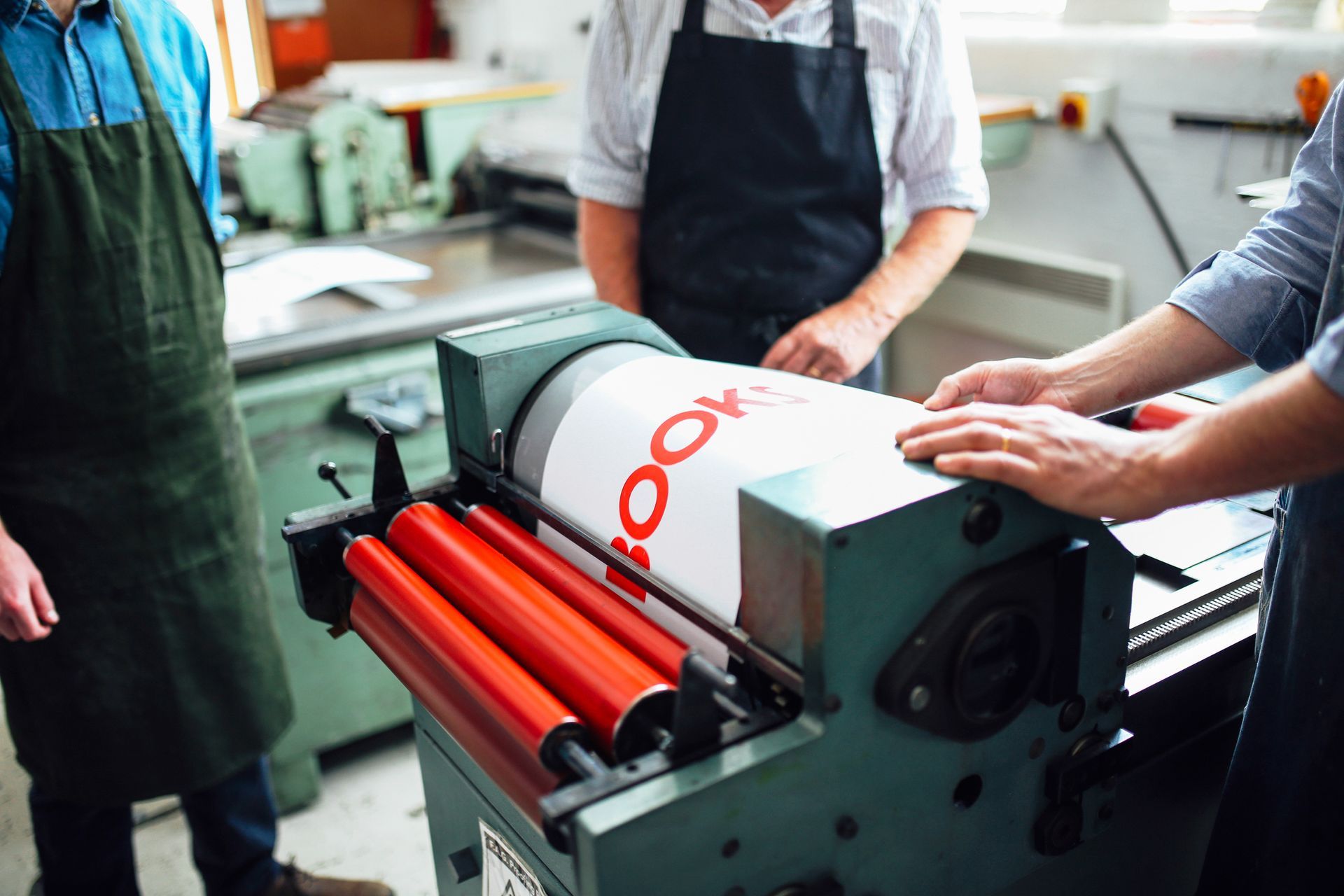 Craftspeople being shown how to use a letterpress machine. Craftspeople being shown how to use a letterpress machine.