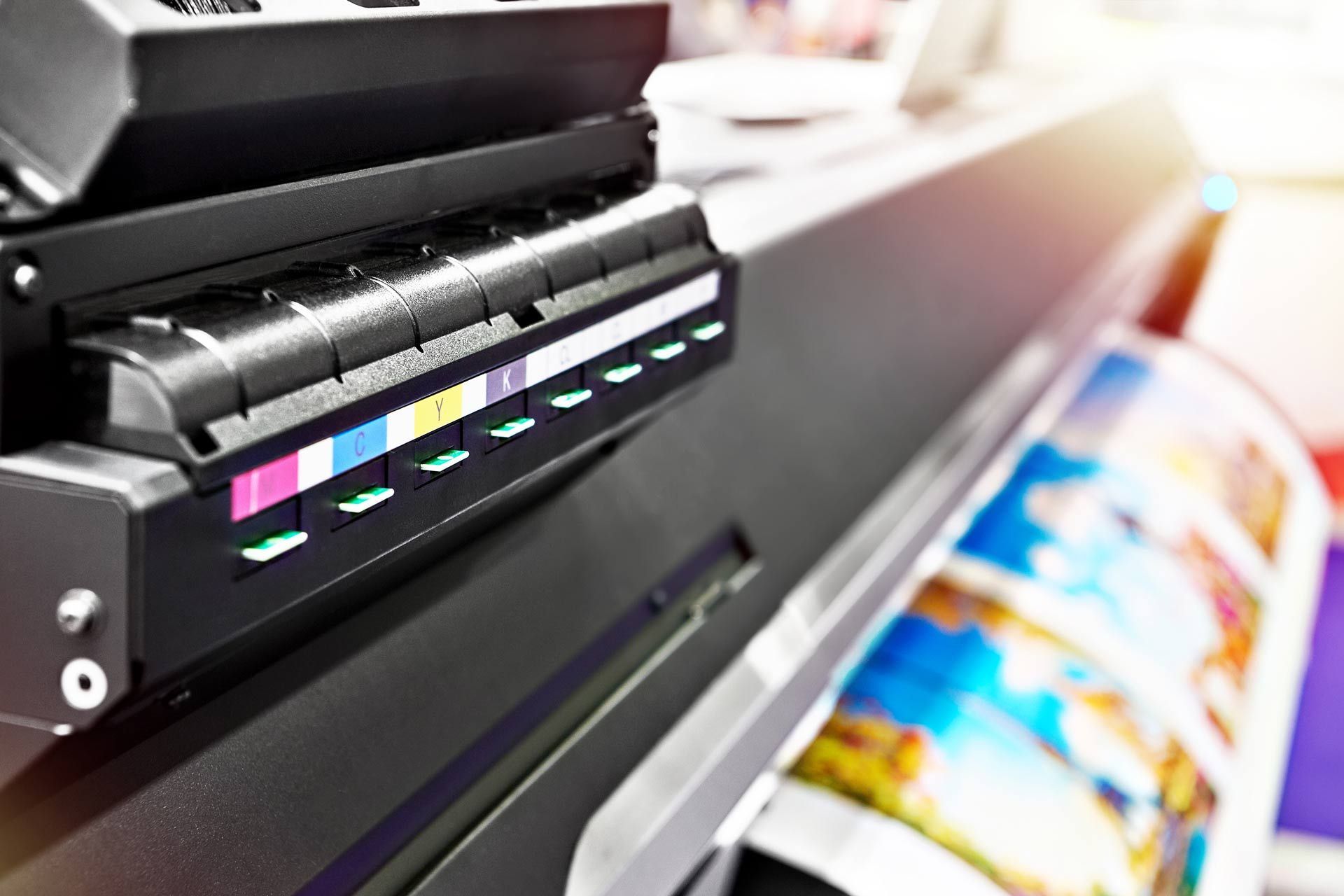 Close-up of CMYK ink cartridges and vibrant print emerging from a digital printer