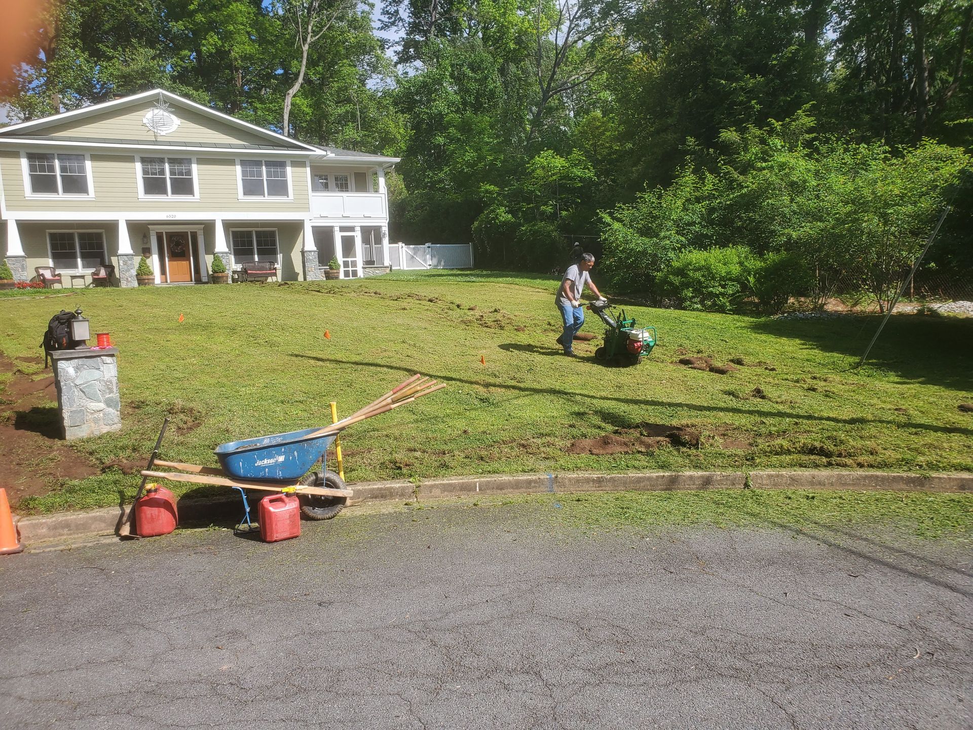 A man is pushing a wheelbarrow in front of a house.