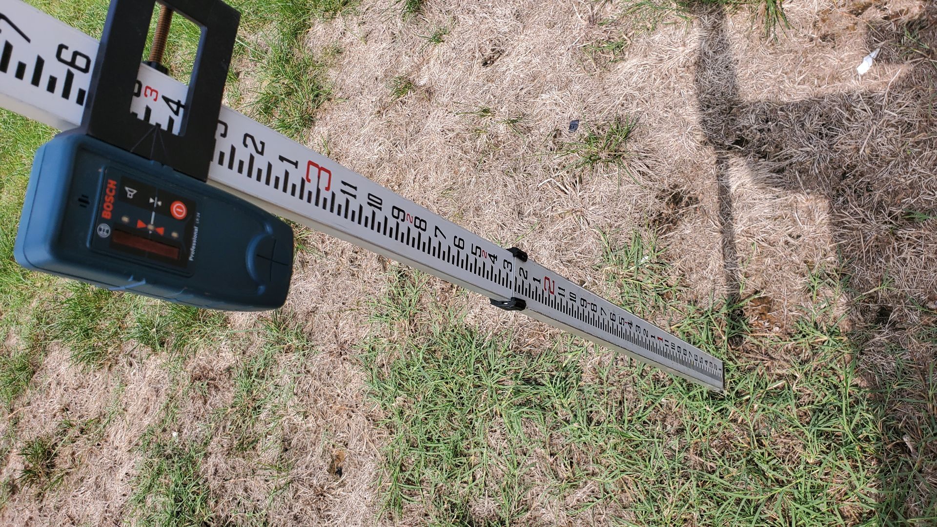 A measuring tape is sitting on top of a lush green field.