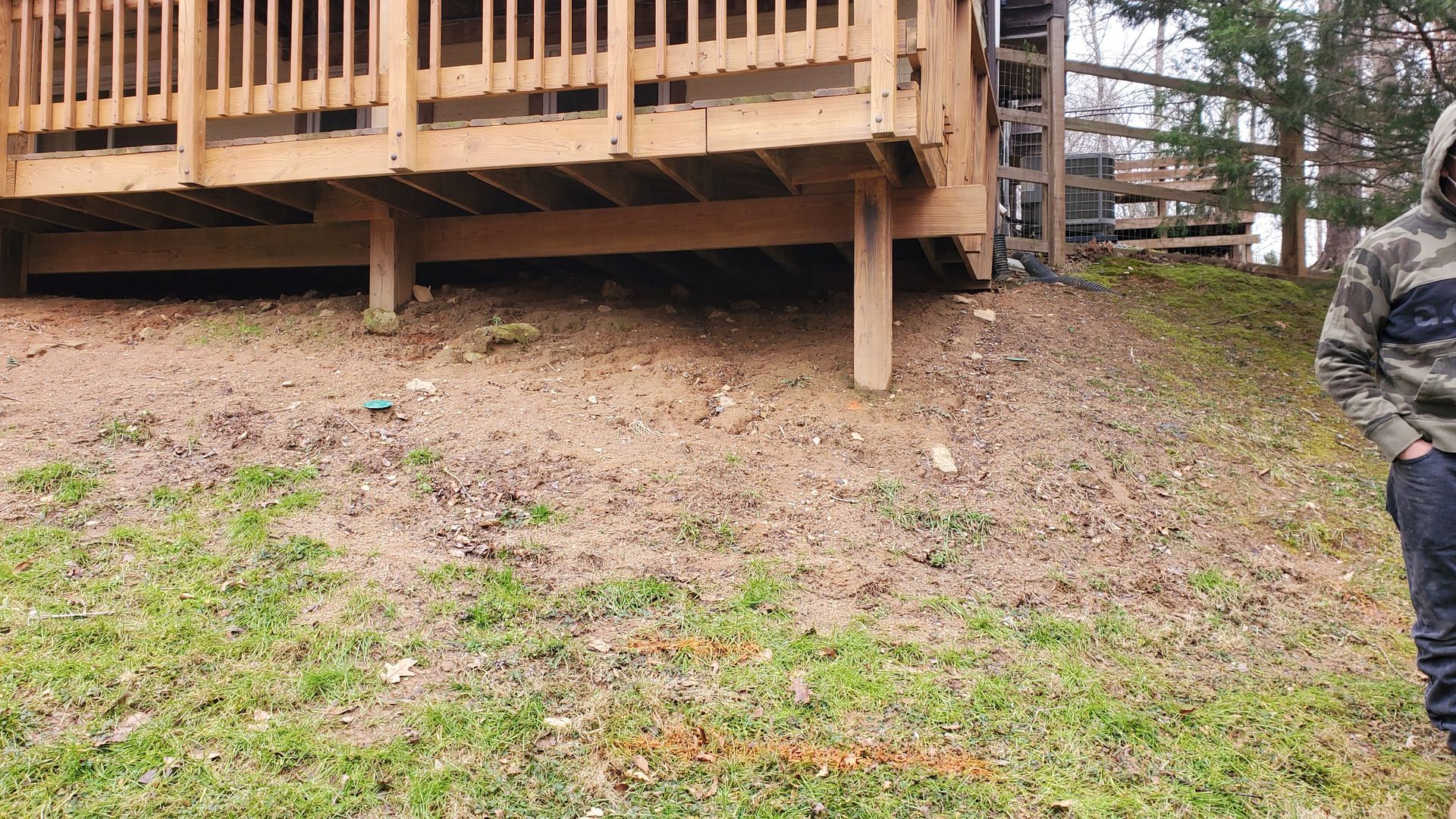 A man is standing in front of a wooden deck.