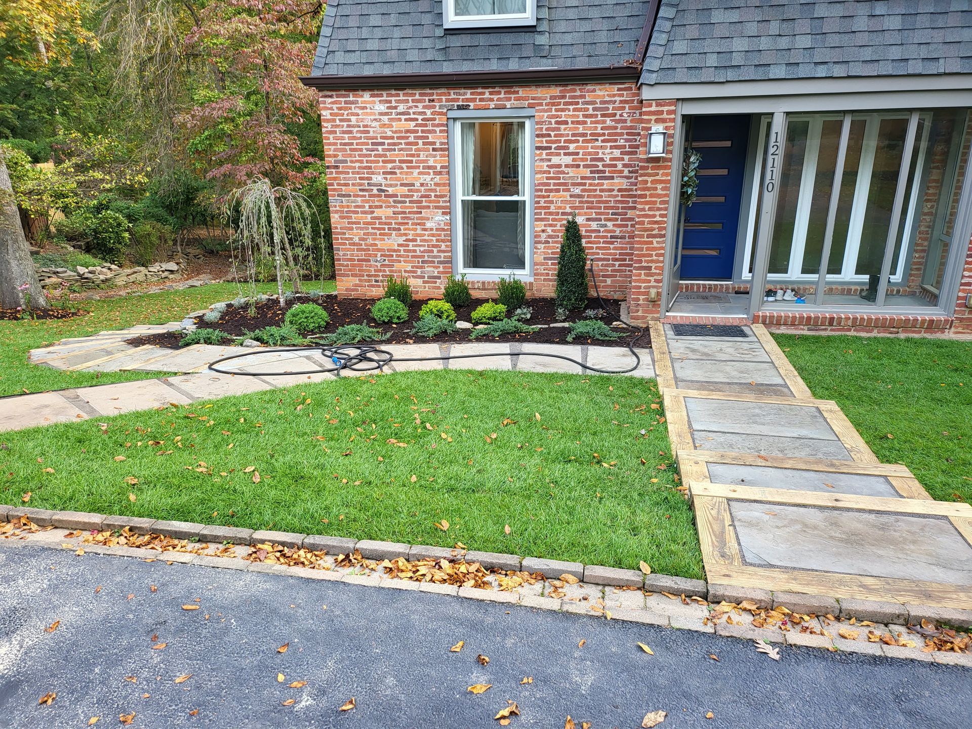 A brick house with a blue door and a stone walkway in front of it.