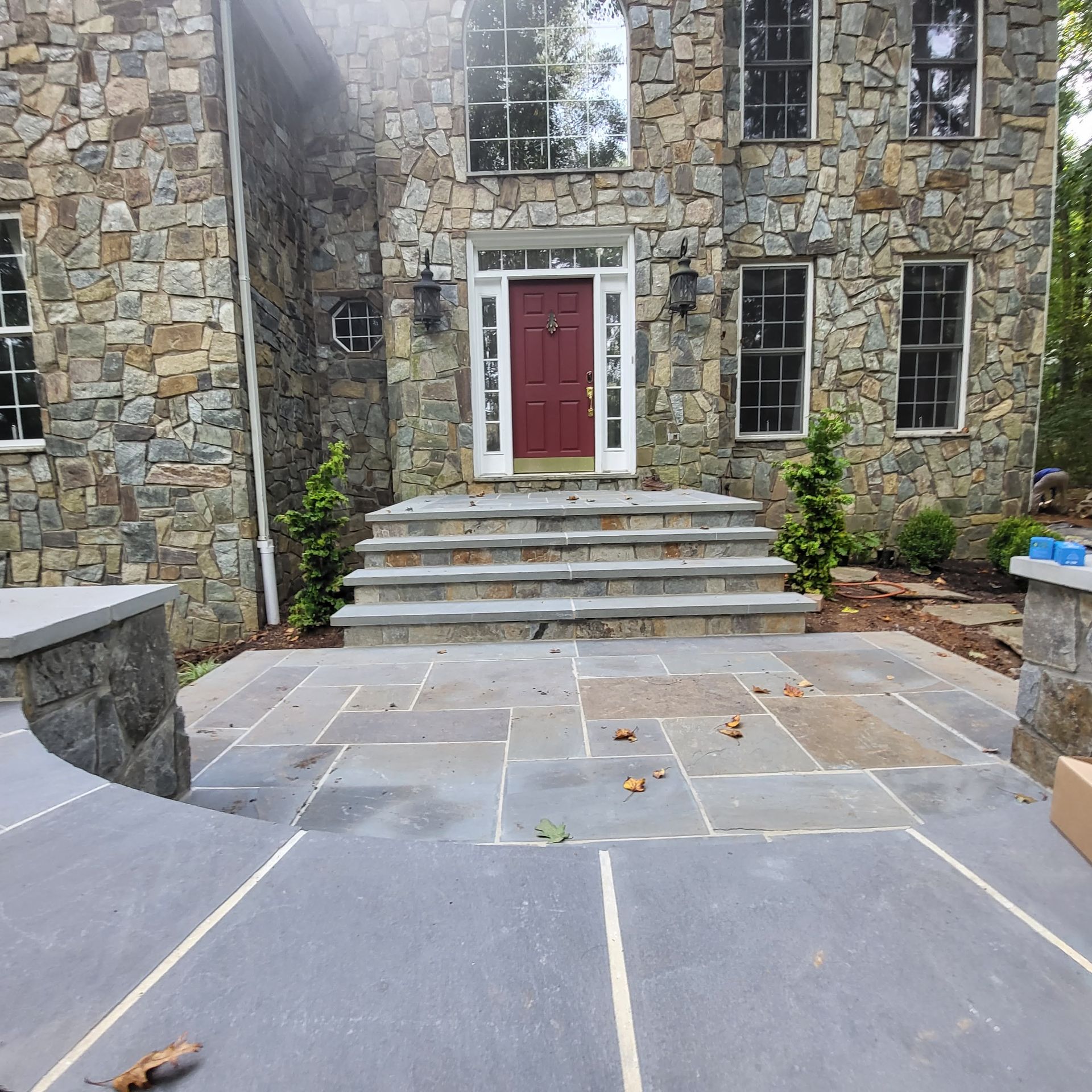 A stone house with a red door and white windows