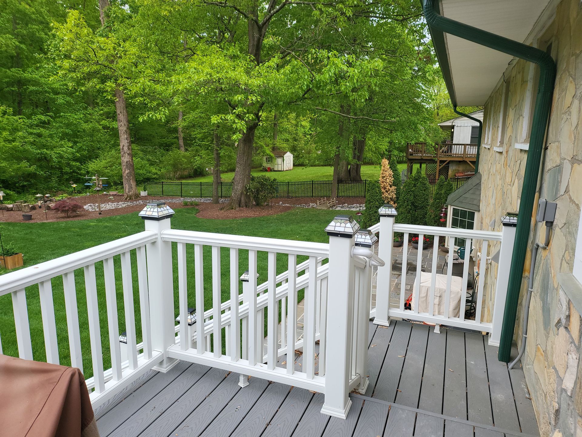 A wooden deck with a white railing and a lawn in the background.